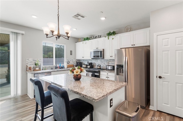 20793 Spring Mountain Rd, Riverside, CA 92507 - kitchen with appliances with stainless steel finishes, a chandelier, light wood-style floors, white cabinetry, and recessed lighting