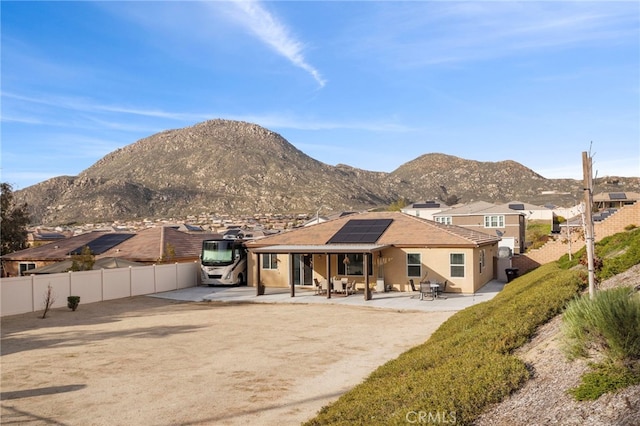 20793 Spring Mountain Rd, Riverside, CA 92507 - back of property featuring solar panels, a patio, a mountain view, a fenced backyard, and stucco siding
