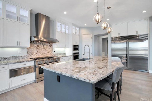 1733 Lemonadeberry Ln, Vista, CA 92084 - kitchen with wall chimney range hood, high end appliances, a warming drawer, light wood-style flooring, and a breakfast bar