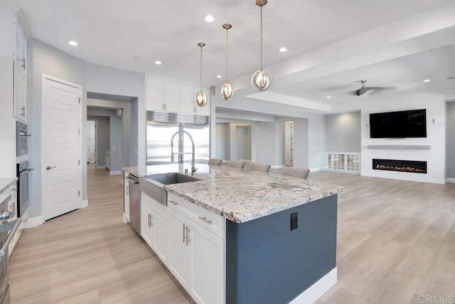 1733 Lemonadeberry Ln, Vista, CA 92084 - kitchen with appliances with stainless steel finishes, a warm lit fireplace, light wood finished floors, white cabinets, and recessed lighting