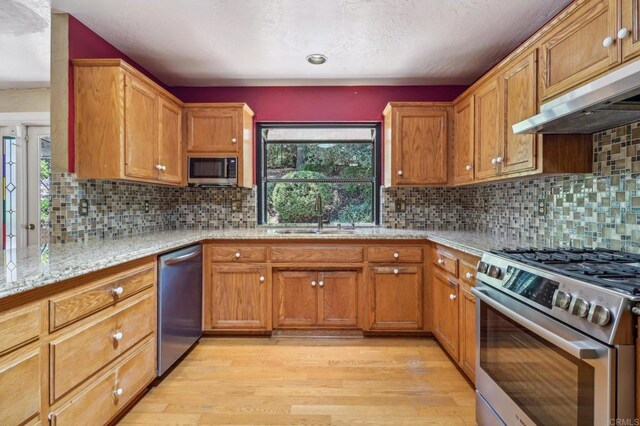 1575 Larson Ln, Fallbrook, CA 92028 - kitchen featuring stainless steel appliances, a sink, under cabinet range hood, light wood-style floors, and healthy amount of natural light