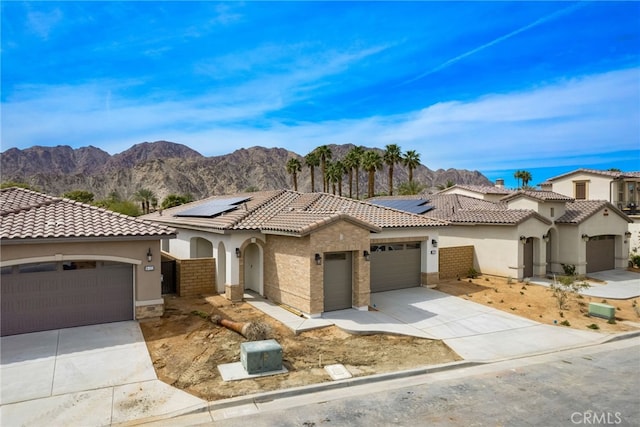 56217 Platinum Way, La Quinta, CA 92253 - mediterranean / spanish home featuring stucco siding, a garage, concrete driveway, a tiled roof, and roof mounted solar panels
