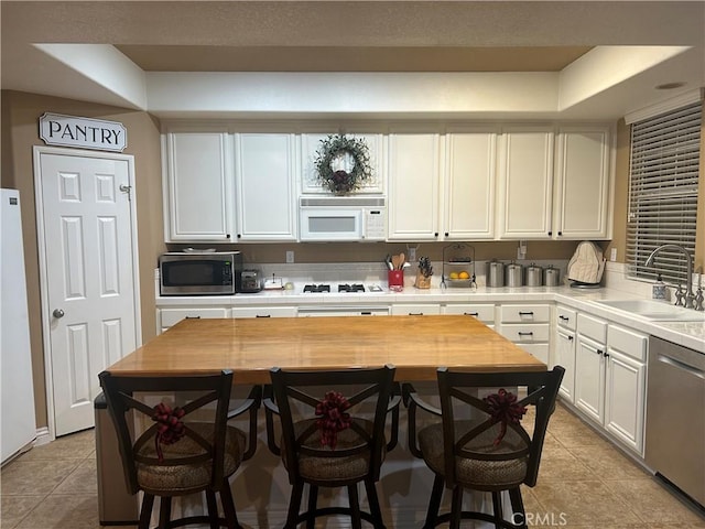 27951 Via De Costa, San Juan Capistrano, CA 92675 - kitchen featuring stainless steel appliances, a sink, light tile patterned floors, white cabinets, and a breakfast bar area