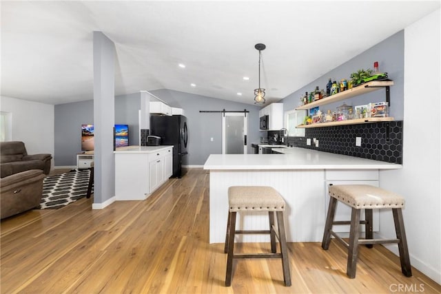 38448 95th St E, Palmdale, CA 93591 - kitchen with black appliances, a barn door, lofted ceiling, a peninsula, and light wood-type flooring