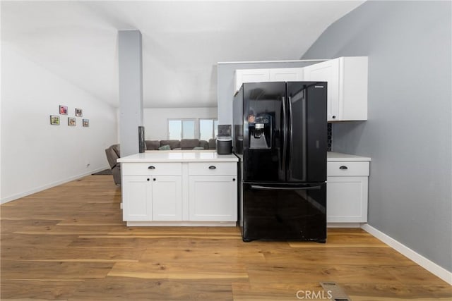 38448 95th St E, Palmdale, CA 93591 - kitchen with black fridge with ice dispenser, vaulted ceiling, white cabinetry, light countertops, and baseboards