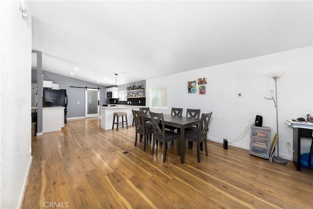 38448 95th St E, Palmdale, CA 93591 - dining area with a barn door, vaulted ceiling, wood-type flooring, baseboards, and recessed lighting