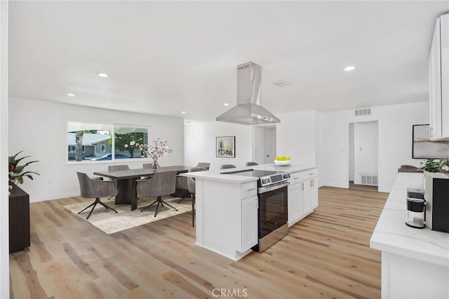 28870 Crosby Dr, Menifee, CA 92586 - kitchen featuring electric stove, island exhaust hood, white cabinets, light wood-style flooring, and recessed lighting