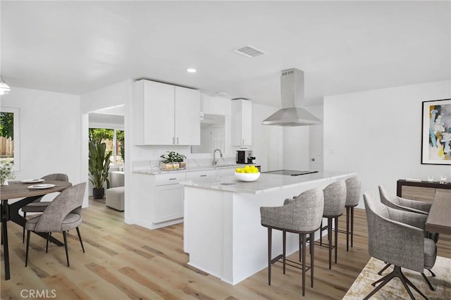 28870 Crosby Dr, Menifee, CA 92586 - kitchen featuring island range hood, black electric cooktop, light wood-type flooring, white cabinetry, and recessed lighting