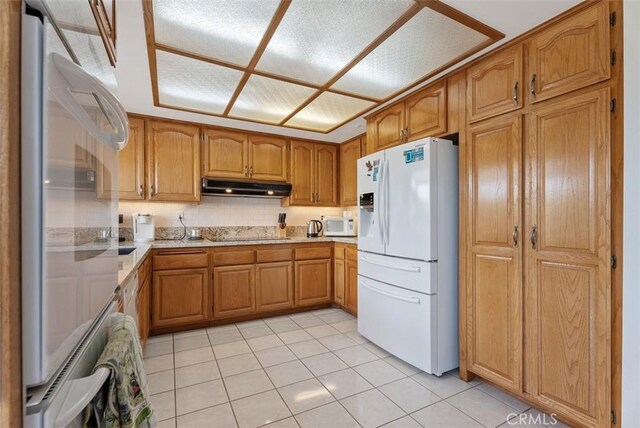 29206 Alfieri St, Laguna Niguel, CA 92677 - kitchen featuring white appliances, under cabinet range hood, light tile patterned floors, and brown cabinets
