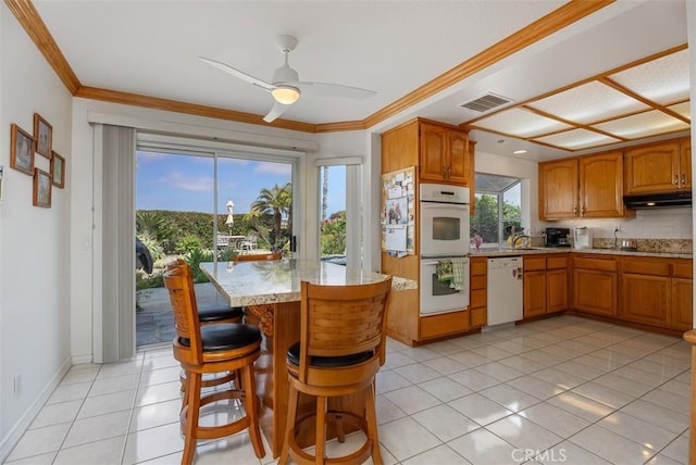 29206 Alfieri St, Laguna Niguel, CA 92677 - kitchen with white appliances, under cabinet range hood, crown molding, light tile patterned floors, and brown cabinetry