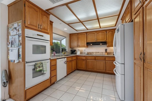 29206 Alfieri St, Laguna Niguel, CA 92677 - kitchen with white appliances, under cabinet range hood, brown cabinetry, light stone counters, and light tile patterned floors