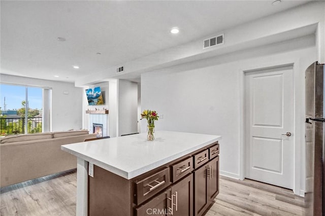 3540 W Savanna St, Anaheim, CA 92804 - kitchen featuring dark brown cabinetry, a glass covered fireplace, light wood-style floors, light countertops, and recessed lighting