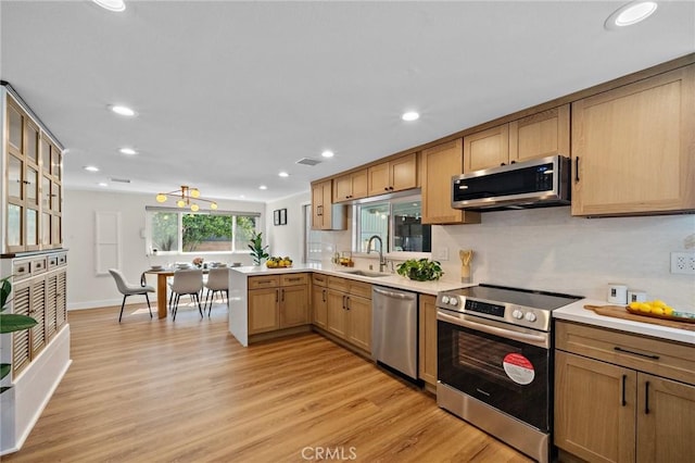 5742 Thelma Ave, La Palma, CA 90623 - kitchen with appliances with stainless steel finishes, a peninsula, light countertops, light wood-style floors, and a sink