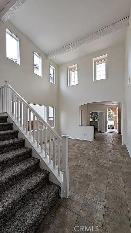 3929 Albillo, Perris, CA 92571 - stairs featuring a towering ceiling, beam ceiling, arched walkways, and baseboards