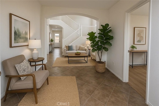 3929 Albillo, Perris, CA 92571 - living room with stairway, arched walkways, baseboards, and dark tile patterned flooring