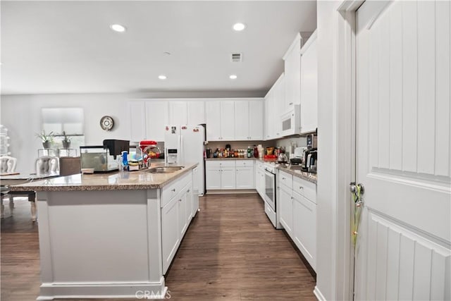 2219 Albatross Way, San Jacinto, CA 92582 - kitchen featuring white appliances, dark wood finished floors, a sink, white cabinets, and a center island with sink