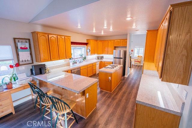 36884 Hidden Trail Ct, Winchester, CA 92596 - kitchen featuring a center island, dark wood-style flooring, light countertops, and a peninsula