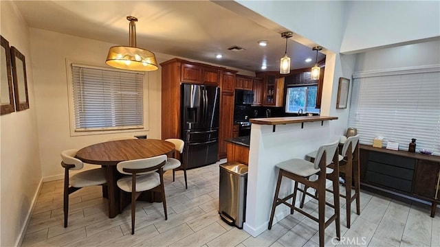 402 Hartzell Ave, Redlands, CA 92374 - kitchen featuring black appliances, a breakfast bar, decorative light fixtures, baseboards, and a peninsula