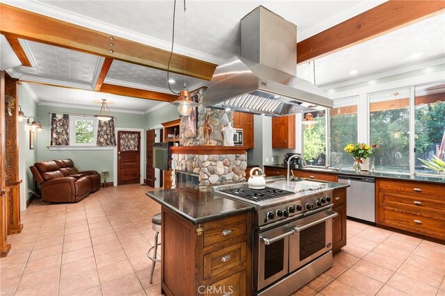337 S Center St, Redlands, CA 92373 - kitchen featuring appliances with stainless steel finishes, island exhaust hood, brown cabinetry, light tile patterned flooring, and beam ceiling