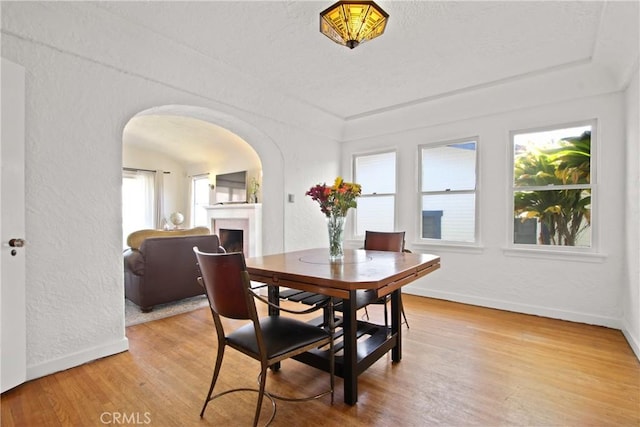 1247 W 17th St, San Pedro, CA 90731 - dining area with arched walkways, a fireplace, baseboards, light wood-style floors, and a textured wall
