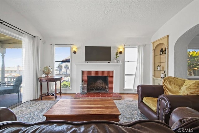 1247 W 17th St, San Pedro, CA 90731 - living area with lofted ceiling, wood finished floors, a brick fireplace, a textured ceiling, and arched walkways