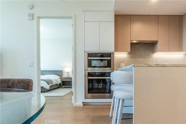 877 Francisco St Unit 1512, Los Angeles, CA 90017 - kitchen with double oven, light wood-style flooring, and under cabinet range hood