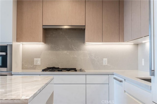 877 Francisco St Unit 1512, Los Angeles, CA 90017 - kitchen with stainless steel gas stovetop, light countertops, backsplash, under cabinet range hood, and modern cabinets