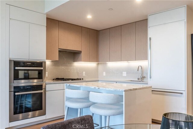 877 Francisco St Unit 1512, Los Angeles, CA 90017 - kitchen with gas stovetop, double oven, light stone counters, a kitchen breakfast bar, and tasteful backsplash