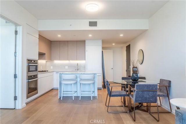 877 Francisco St Unit 1512, Los Angeles, CA 90017 - kitchen with oven, a breakfast bar area, light wood finished floors, and recessed lighting
