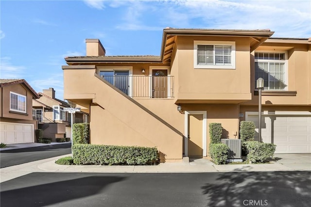 8039 E Snapdragon Ln, Anaheim, CA 92808 - view of front of property with stucco siding, central AC unit, a chimney, and a garage