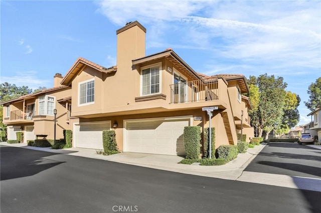 8039 E Snapdragon Ln, Anaheim, CA 92808 - view of front of home with a chimney, stucco siding, a balcony, and a garage