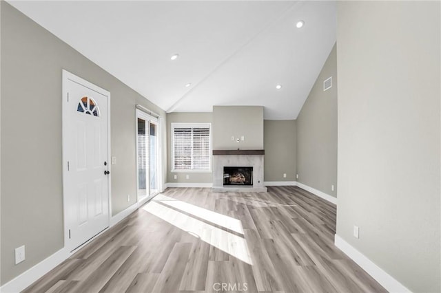 8039 E Snapdragon Ln, Anaheim, CA 92808 - unfurnished living room featuring light wood-style flooring, vaulted ceiling, baseboards, a premium fireplace, and recessed lighting