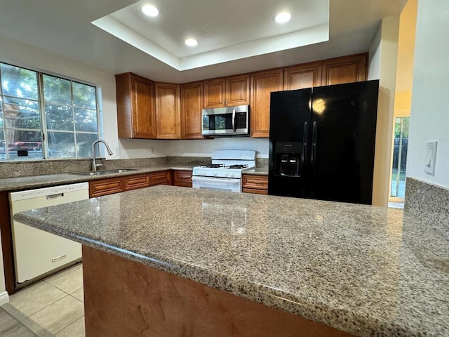 1103 Manzana Way, San Diego, CA 92139 - kitchen featuring white appliances, brown cabinets, a tray ceiling, dark stone counters, and light tile patterned floors