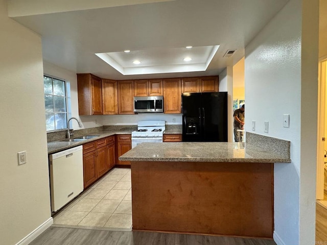 1103 Manzana Way, San Diego, CA 92139 - kitchen with white appliances, a tray ceiling, dark stone counters, light wood finished floors, and a peninsula