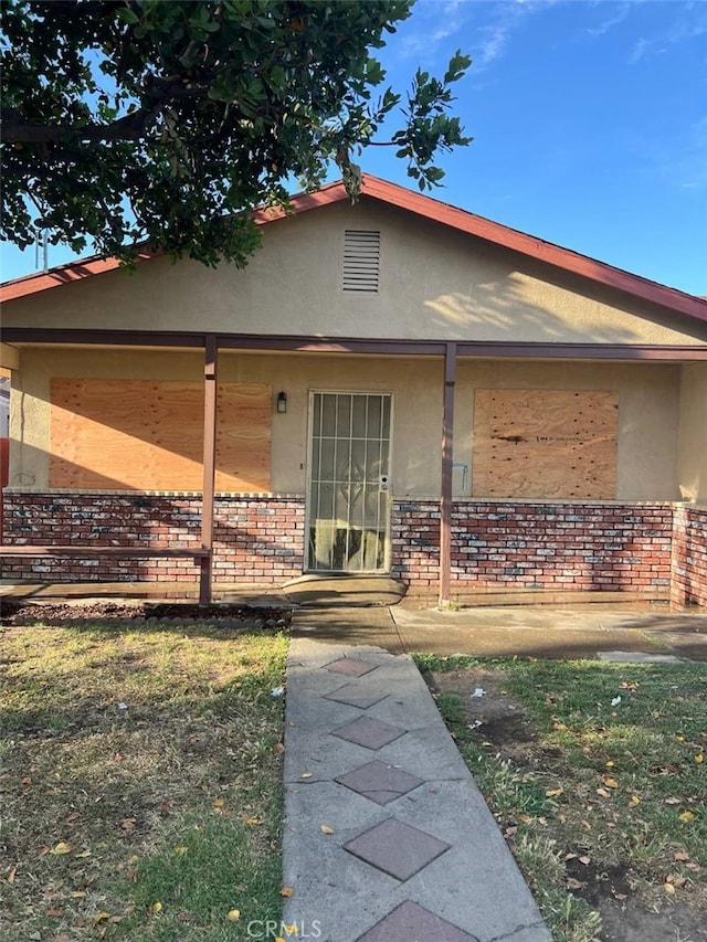 1311 W 1st St, Merced, CA 95341 - view of front of property with stucco siding, a porch, and brick siding