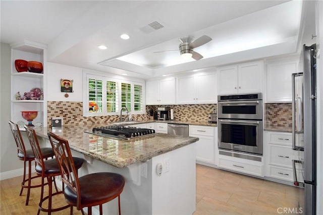20950 Oxnard St Unit 11, Woodland Hills, CA 91367 - kitchen featuring stainless steel appliances, a peninsula, white cabinetry, light stone countertops, and a kitchen bar