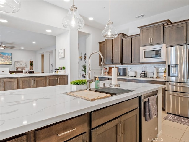 17028 Ta Ki Pi Rd, Apple Valley, CA 92307 - kitchen with stainless steel appliances, a sink, light stone countertops, decorative light fixtures, and recessed lighting