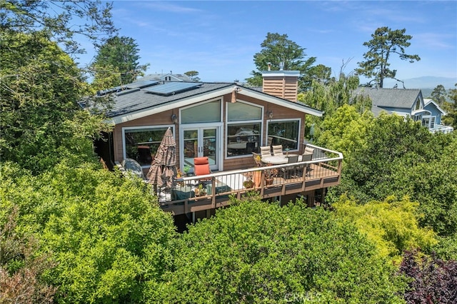 1760 Stuart St, Cambria, CA 93428 - back of property with a deck, roof mounted solar panels, a chimney, and french doors