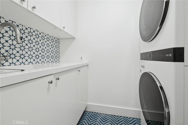 4322 Alcove Ave, Studio City, CA 91604 - laundry room with stacked washer / dryer, cabinet space, and baseboards