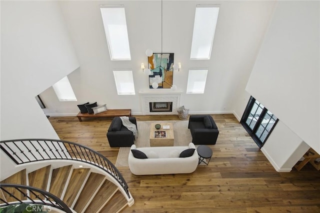 4322 Alcove Ave, Studio City, CA 91604 - living room featuring a fireplace, a towering ceiling, wood finished floors, a skylight, and baseboards