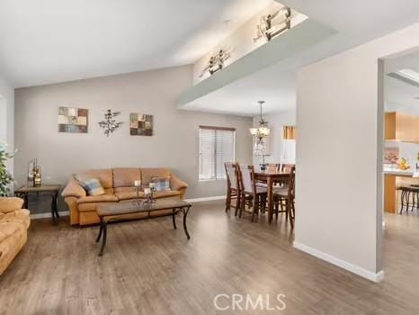 11191 Baker Ln, Riverside, CA 92505 - living room with baseboards, wood finished floors, vaulted ceiling, and a chandelier