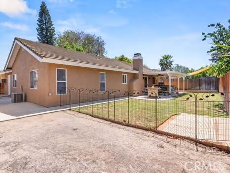 11191 Baker Ln, Riverside, CA 92505 - back of property with a patio area, stucco siding, central AC unit, and a chimney