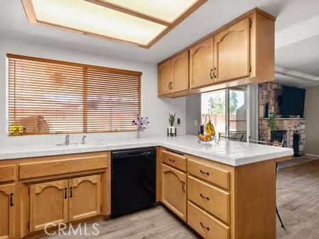 11191 Baker Ln, Riverside, CA 92505 - kitchen featuring black dishwasher, a peninsula, light countertops, a fireplace, and light wood-style floors