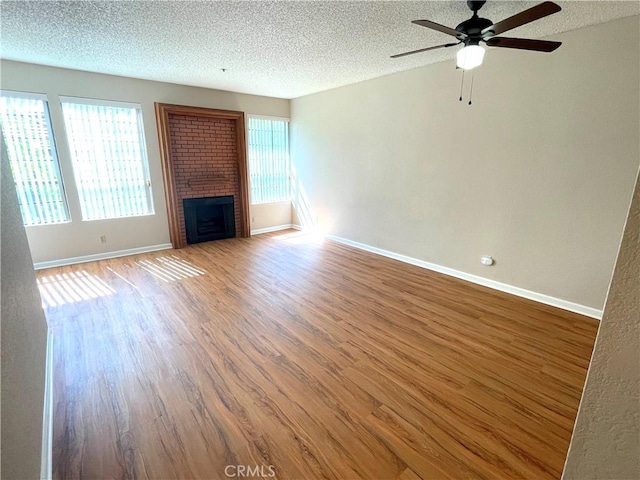 2563 Plaza Del Amo Unit 304, Torrance, CA 90503 - unfurnished living room featuring healthy amount of natural light, a textured ceiling, wood finished floors, a ceiling fan, and a brick fireplace
