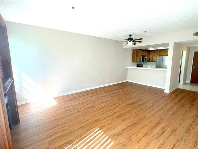 2563 Plaza Del Amo Unit 304, Torrance, CA 90503 - unfurnished living room with light wood-type flooring, baseboards, ceiling fan, and a textured ceiling