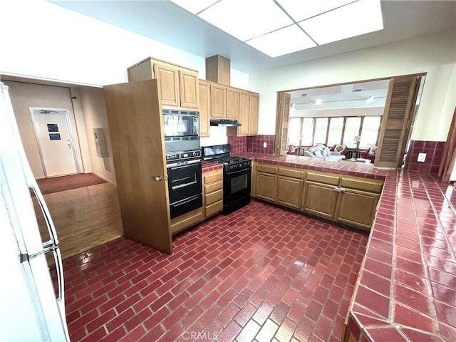 2563 Plaza Del Amo Unit 304, Torrance, CA 90503 - kitchen featuring black appliances, tile counters, under cabinet range hood, brick flooring, and light brown cabinets