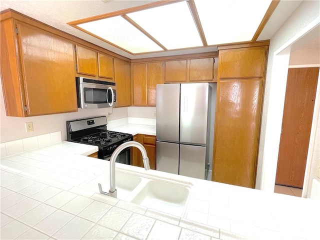 2563 Plaza Del Amo Unit 304, Torrance, CA 90503 - kitchen with appliances with stainless steel finishes, a sink, brown cabinets, and tile counters