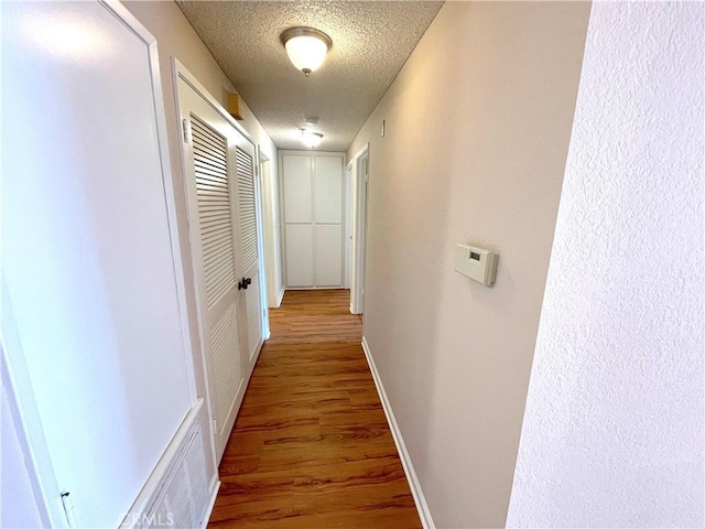 2563 Plaza Del Amo Unit 304, Torrance, CA 90503 - hallway featuring a textured ceiling, wood finished floors, and baseboards