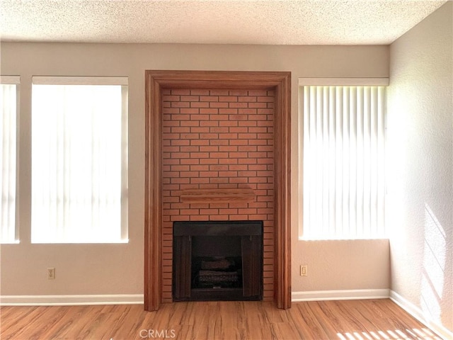 2563 Plaza Del Amo Unit 304, Torrance, CA 90503 - unfurnished living room with wood finished floors, baseboards, a large fireplace, and a textured ceiling