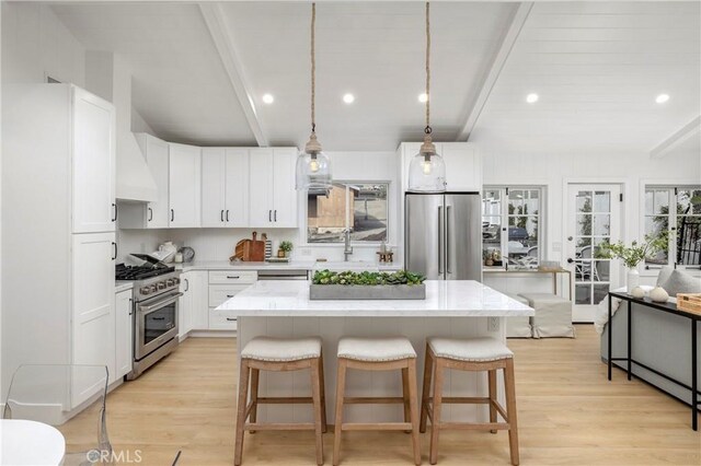 556 Through St, Laguna Beach, CA 92651 - kitchen with appliances with stainless steel finishes, beam ceiling, light wood-style flooring, a kitchen island, and a kitchen breakfast bar
